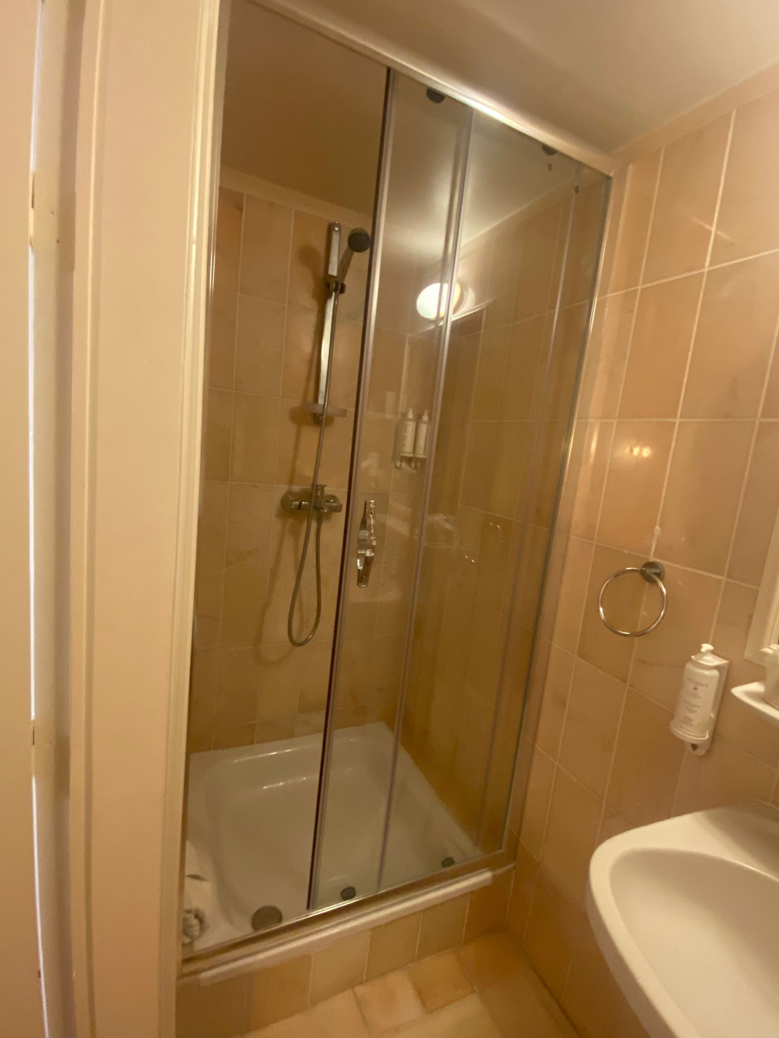 Un box de ducha con paredes de vidrio, equipado con ducha de mano y rociador manual.