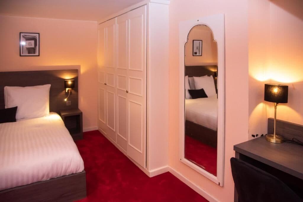 Een hotelkamer met een bed, een kledingkast, een bureau en een spiegel.