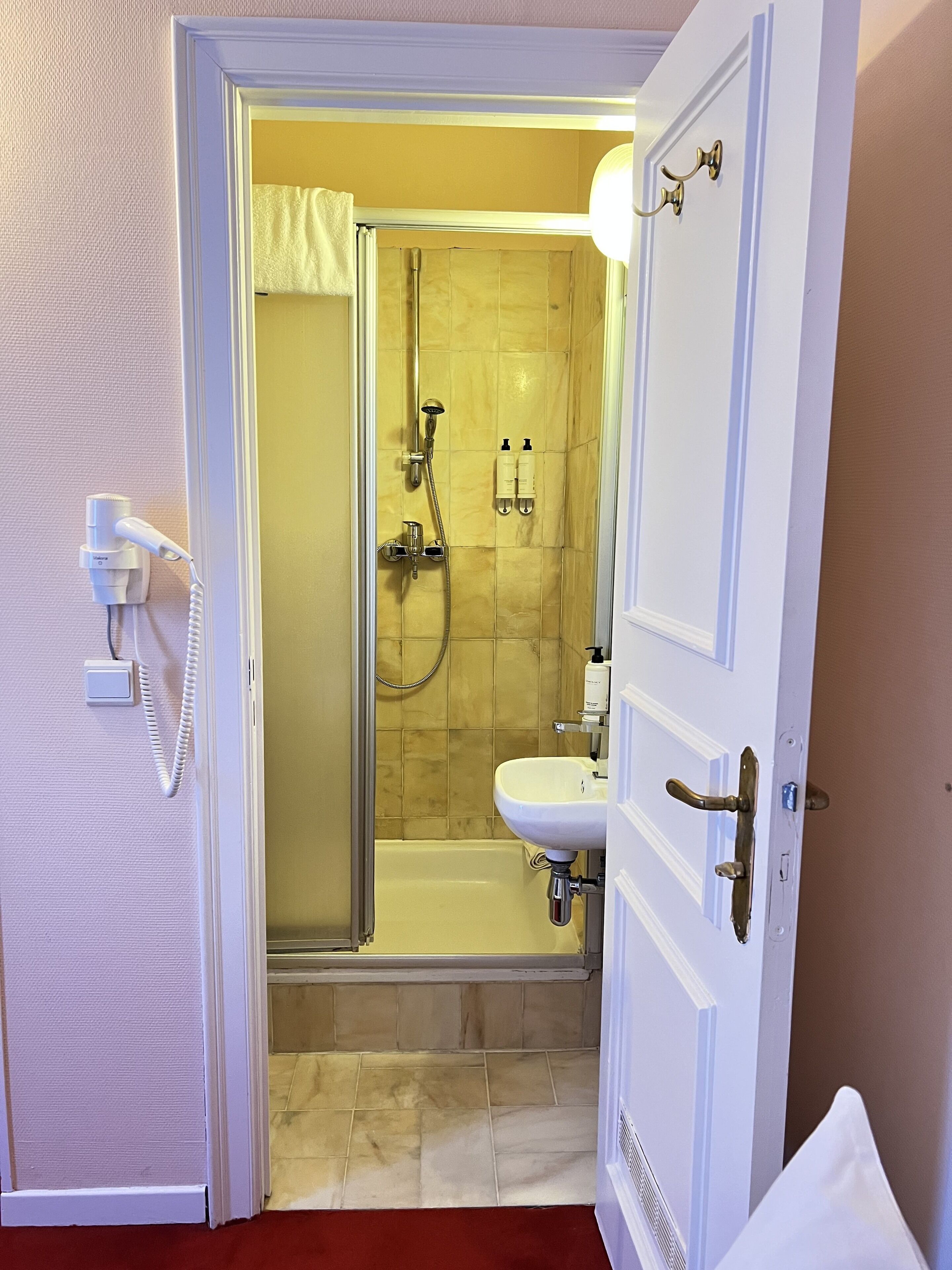 Un baño de hotel con ducha, lavabo e inodoro.