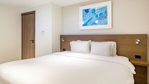 A hotel room with a large bed, a wooden headboard, a framed abstract painting, and a wooden door. - Keito 2BR APT #K3-3 min to Palm Beach-Sleeps 4 (Noord)