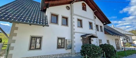 A two-story building with a tiled roof, stone base, and multiple windows.