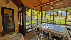 A wooden interior with a large window, a table, and chairs. - Zotlar House (Bohinj)
