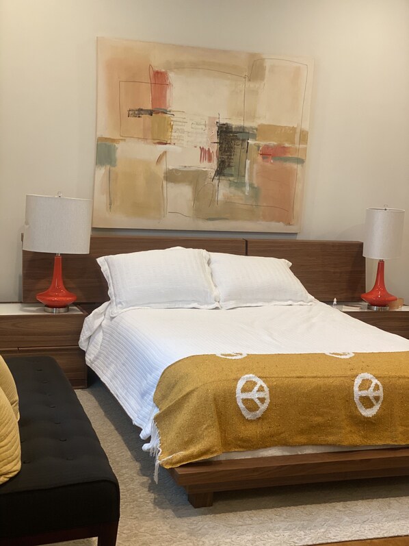 A neatly made bed with white linens, a brown throw blanket with peace symbols, and two red lamps on wooden nightstands. - Amazing modern home on the 14th hole of the Pines golf course in Diamondhead MS! (Diamondhead)