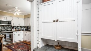 Una cocina con gabinetes blancos, un microondas y un ventilador de techo.