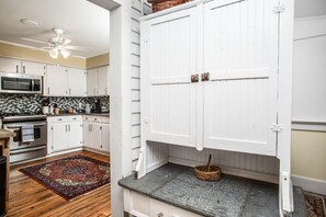 Una cocina con gabinetes blancos, un microondas y un ventilador de techo.