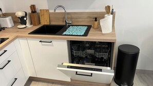 A kitchen with a black sink, wooden countertop, and a dishwasher built into the cabinetry. - Charming gîte in Carantec, 44m² of happiness between sea, calm and barbecue! (Carantec)