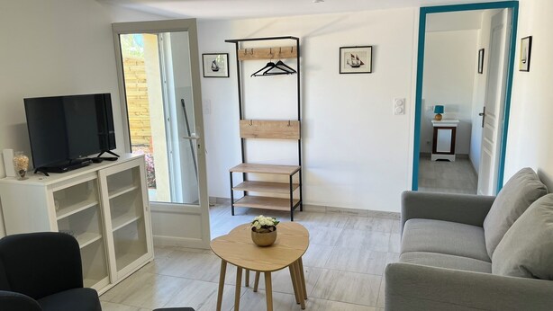 A modern living room with a TV, sofa, and a small table. - Charming gîte in Carantec, 44m² of happiness between sea, calm and barbecue! (Carantec)