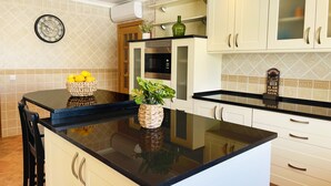 Een moderne keuken met een zwart aanrecht, witte kastjes en een decoratieve klok aan de muur.