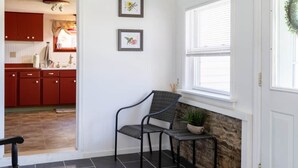 A modern kitchen with red cabinets, a stone fireplace, and a dining area with a chair and table. - Dragonfly Cottage-Pet-friendly, relaxing Wellsboro retreat (Charleston Township)