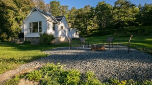 A white house with a stone foundation, surrounded by a gravel driveway and a grassy lawn. - Dragonfly Cottage-Pet-friendly, relaxing Wellsboro retreat (Charleston Township)