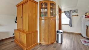 A room with wooden cabinets, a trash bin, and a refrigerator.