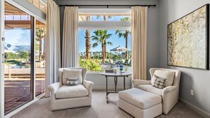 Una habitación con dos sillones, una mesita y un ventanal con cortinas.