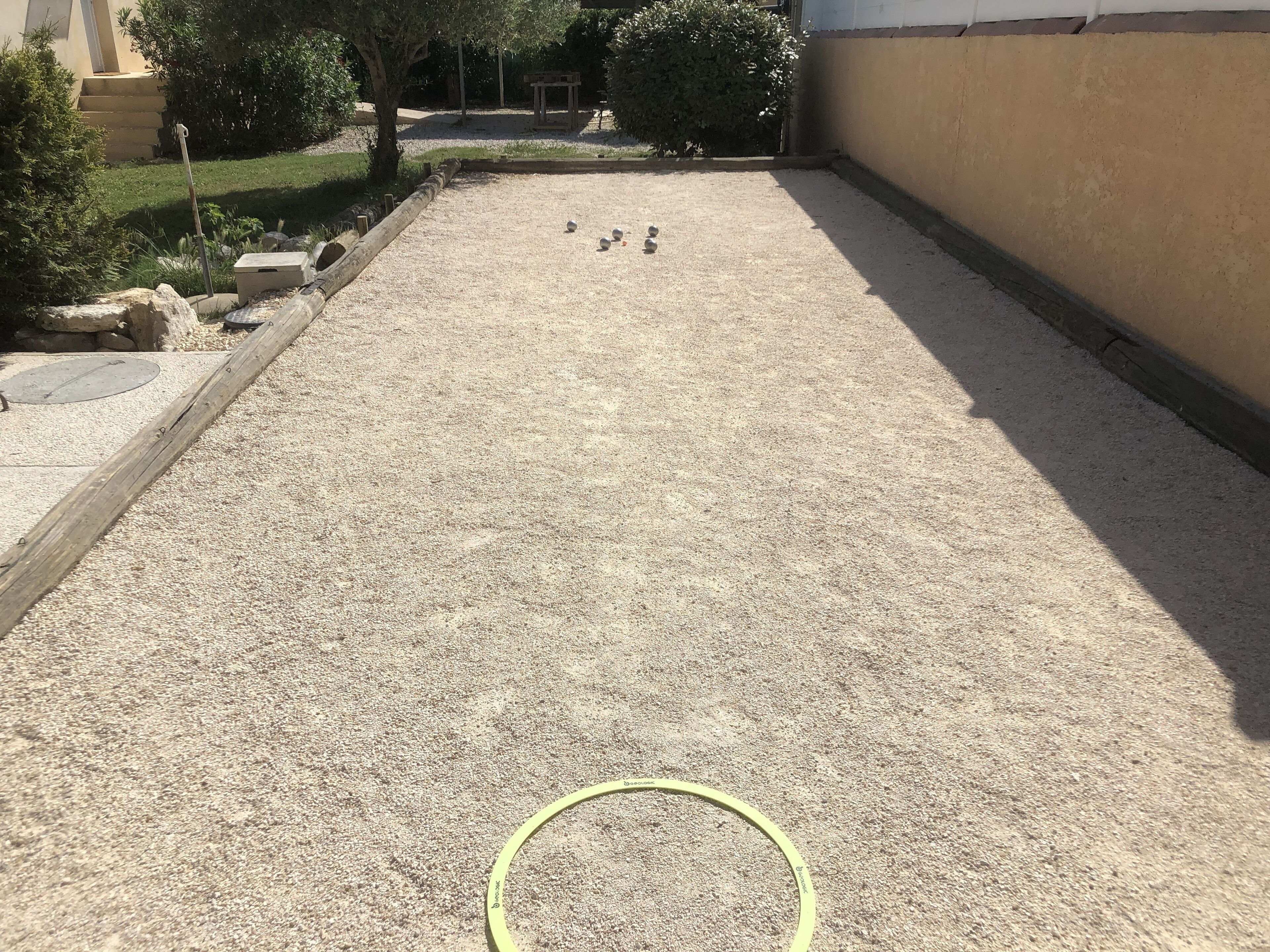 Un cortile con fondo in ghiaia, un tubo da giardino giallo e alcuni oggetti sferici.