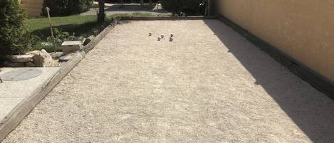 Un cortile con fondo in ghiaia, un tubo da giardino giallo e alcuni oggetti sferici.