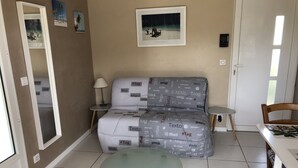 A living room with a sofa, a glass coffee table, a small side table, and a framed picture on the wall. - Studio 20m2 30 minutes from the beach (Saussines)