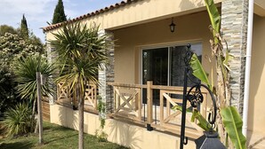 A house with a stone facade, a wooden deck, and a large glass door. - Studio 20m2 30 minutes from the beach (Saussines)