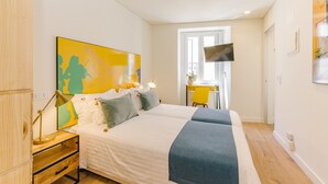 Quarto com cama, mesa de cabeceira, luminária e uma grande pintura abstrata na parede.
