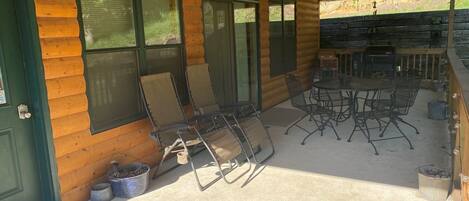 Eine überdachte Terrasse mit Sitzgelegenheiten und Grillplatz.