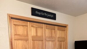 A room with a wooden wardrobe, a sign above it, and a television on the wall. - Cozy Cabin get away - walking distant to beach (Crofton)