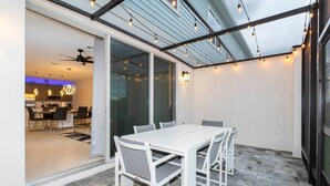 A covered patio with a white table and chairs, a ceiling fan, and string lights. - Exclusive at Reunion Golf View Resort Style 764 (Celebration)