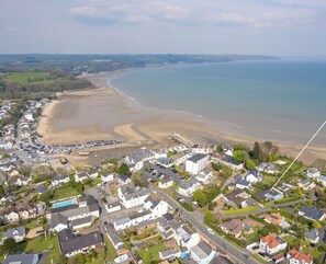 Vista aérea de un pueblo costero con playa, casas y una carretera que llega al mar.