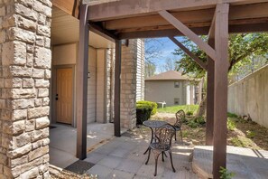 A covered patio with stone pillars, a door, and a small table with chairs.