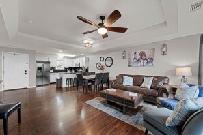 A spacious living area with a dining table, a sofa, and a ceiling fan.