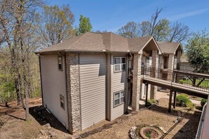 A two-story house with a stone foundation, a covered porch, and a small deck.