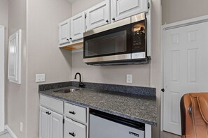 A compact kitchen with white cabinets, a granite countertop, a built-in microwave, and a dishwasher. - Spacious remodel 5 mn-SDC, 10 mn-Lake, 2BR 2.5BA (Branson West)