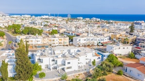 A coastal town with white buildings, a clear blue sky, and a visible beach in the background. - Zoi ayia Napa hotel (Ayia Napa)