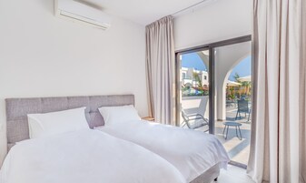 Quarto de hotel com cama, janela com cortinas e vista para o exterior.