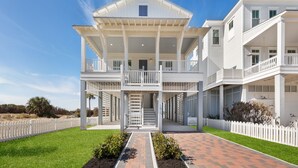 A two-story house with a covered front porch, a staircase leading to the upper level, and a white picket fence.