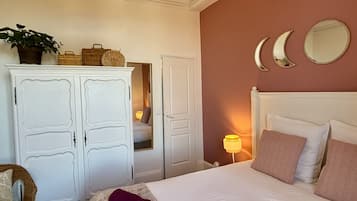 Une chambre à coucher avec un lit, une armoire, un miroir et une lampe de chevet.