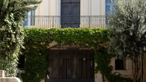 A building with a central entrance, two balconies on the upper floor, and a covered entrance with a door. - Casa Belle (Sérignan)