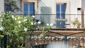 A balcony with a wrought iron railing, a potted plant, and a table with chairs. - Casa Belle (Sérignan)