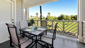 Un balcone con un tavolo apparecchiato per quattro, affaccia su un paesaggio verde con alberi e cielo sereno.