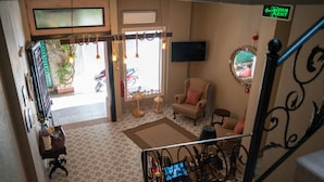 A staircase leading to a room with patterned flooring, a chair, a table with a laptop, and a TV mounted on the wall. - Harakop Otel (Ayvalik)