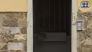 Una puerta con un cartel con el número 22, una reja de metal y un muro de piedra.
