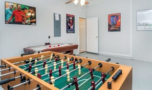 Ett rum med ett fotbollsspel, ett biljardbord och en dörr som leder till ett annat rum.