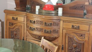 A wooden dresser with a large mirror, a glass table, and a chair.
