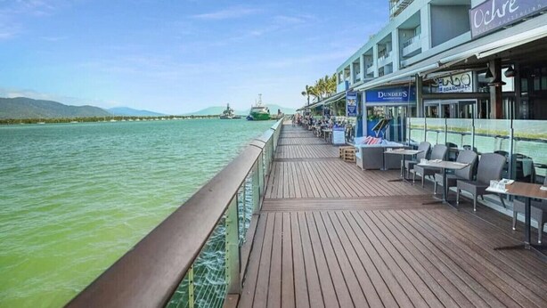 A cruise ship deck with outdoor seating, a view of the sea, and a restaurant named 'Ochre' on the right.