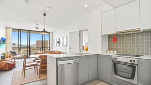 A modern kitchen with a dishwasher, oven, and a dining area with a table and chairs.