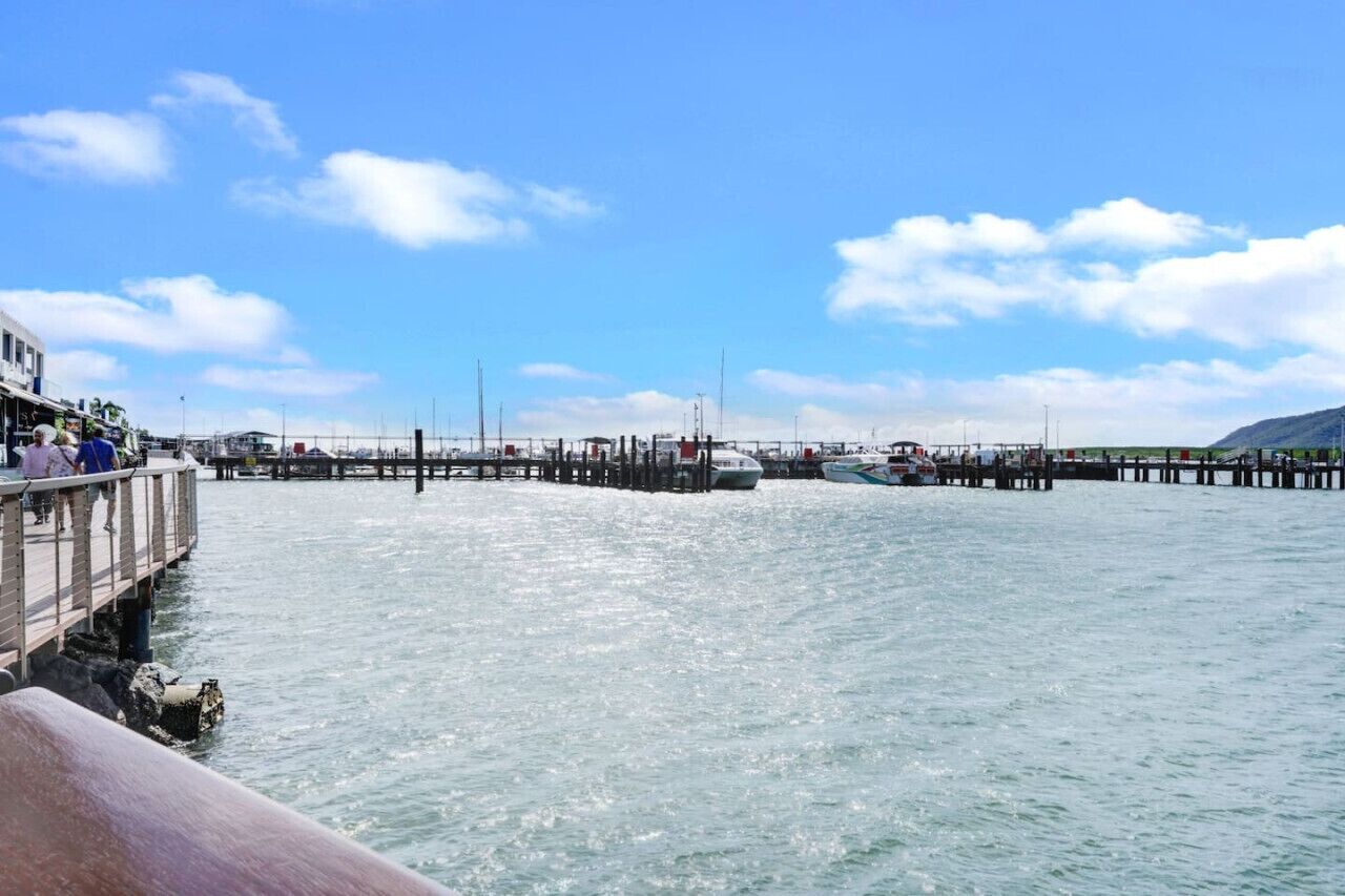 A pier extending into calm water with boats docked at the end.