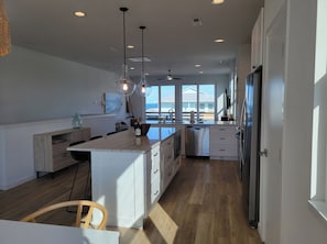 A modern kitchen with a large island, white cabinetry, and a view to the outside.