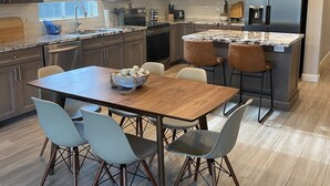 A modern kitchen with granite countertops, stainless steel appliances, and a dining area with a wooden table and chairs. - 🏝5 Min to TOP Shop + dine, 🐶 OK, 900mbps internet (Gilbert)