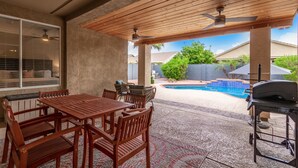 An outdoor patio with a wooden table and chairs, a barbecue grill, and a swimming pool in the background. - 🏝5 Min to TOP Shop + dine, 🐶 OK, 900mbps internet (Gilbert)
