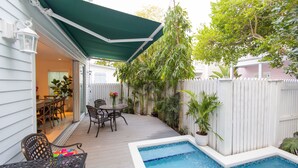 Un jardin avec une piscine, des meubles de patio et un espace salon abrité.