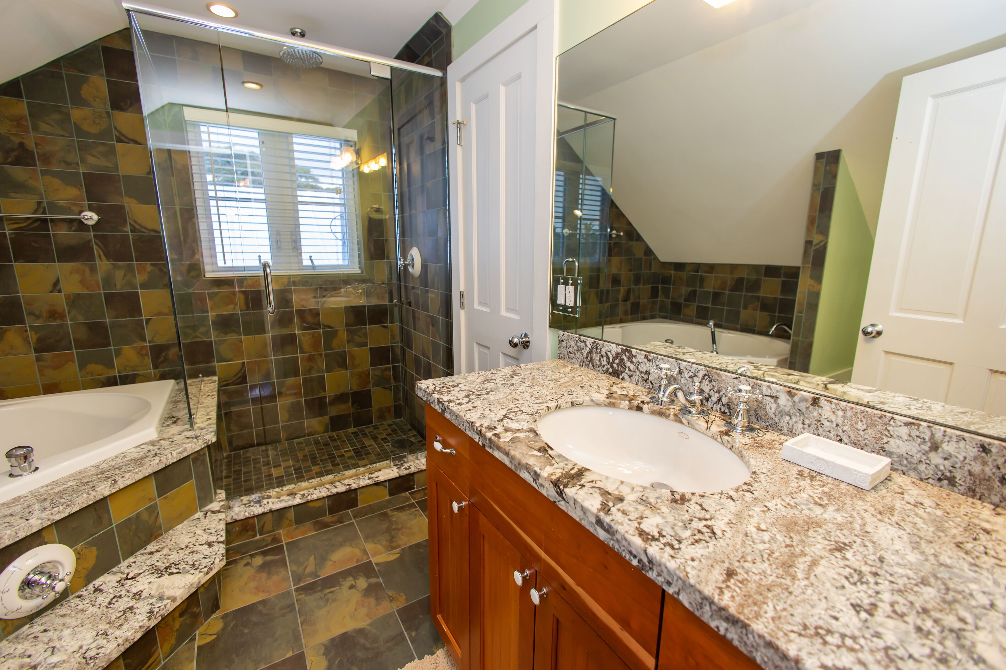 A bathroom with a large sink, a shower, and a glass-enclosed shower area.
