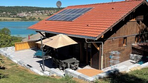 Une maison avec un toit recouvert de tuiles rouges, un panneau solaire, une antenne parabolique et une vue sur un lac.
