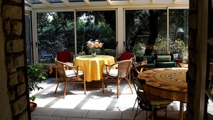 Un patio luminoso con tetto in vetro, mobili in vimini e un tavolo con tovaglia gialla.